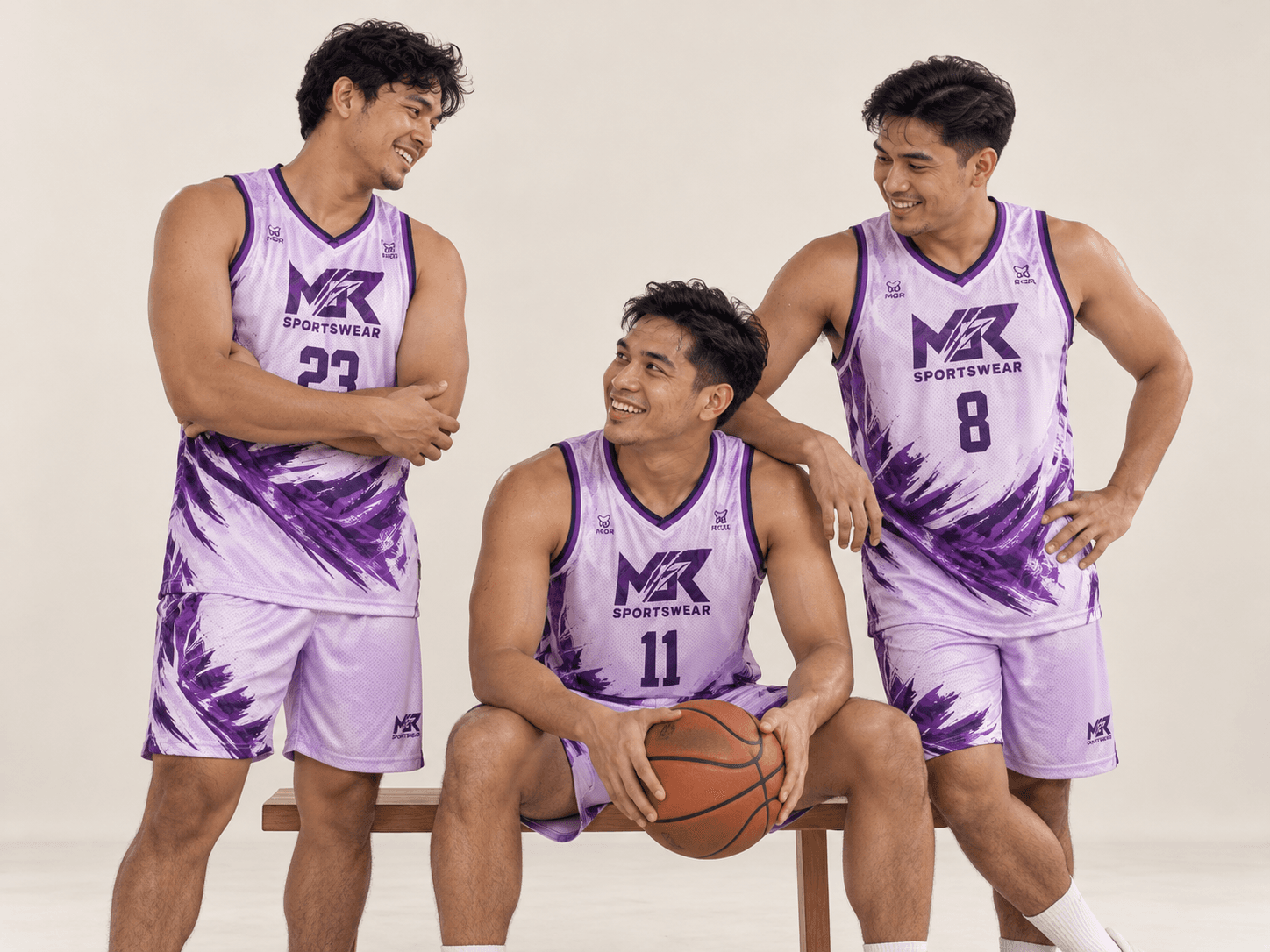 Three basketball teammates in pastel-lilac jerseys during a relaxed studio shoot.